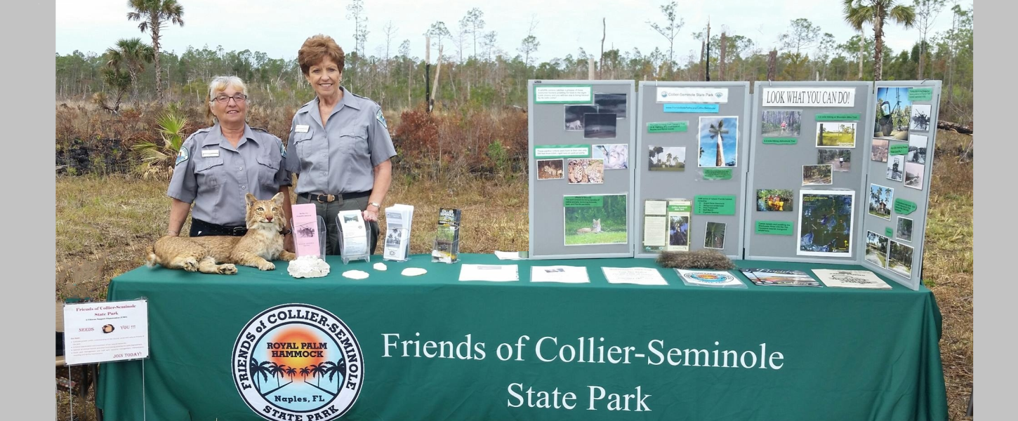 Two members from the Friends of Collier-Seminole State Park hosting display table at a park event.