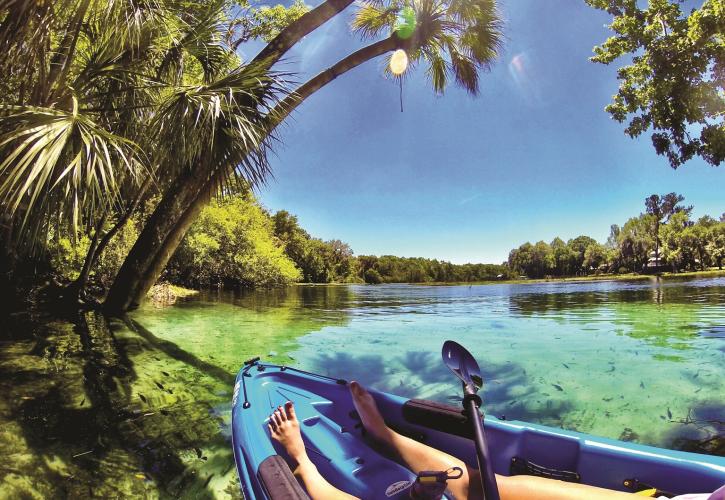 A view of the clear, blue water from the side of a kayak.