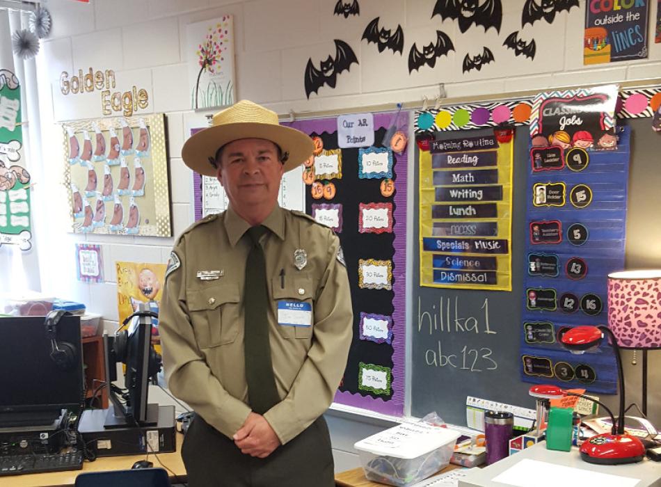 a park ranger in uniform stands in the middle of school classroom