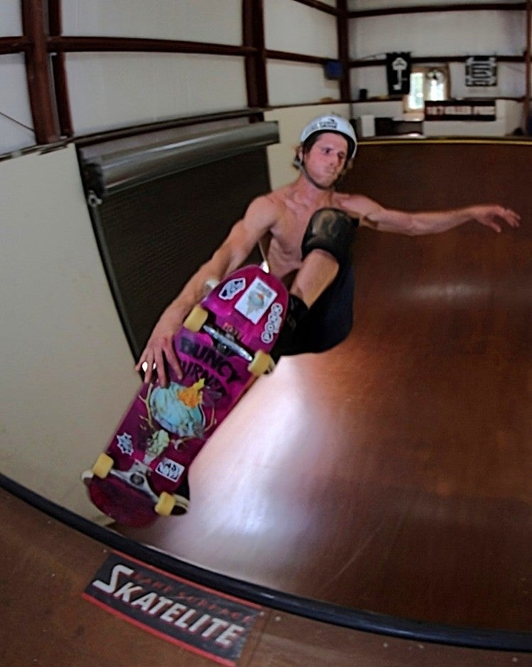 A shirtless skateboarder mid-air on a halfpipe