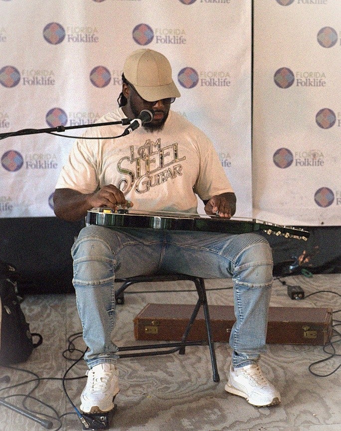 A Black man playing an electric lap steel guitar