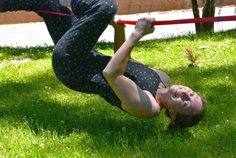 A woman hanging upside down from a slackline
