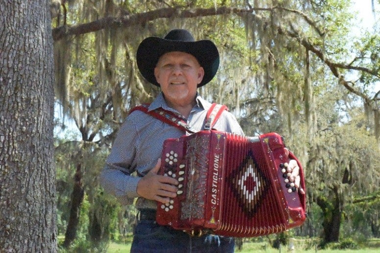 A man in a cowboy hat playing an accordion. 