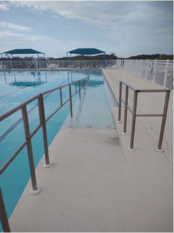 A pool with a metal railing</p>
<p>Description automatically generated