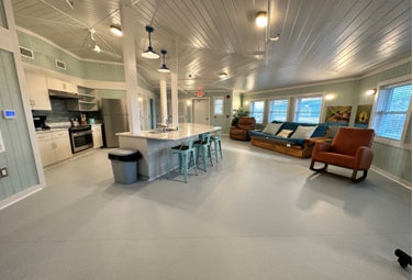 A room with a kitchen and a bar</p>
<p>Description automatically generated