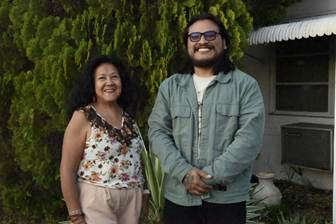 A woman wearing a floral top standing next to a man wearing a denim overshirt