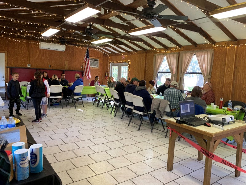 many people sit at tables in a rec hall eating