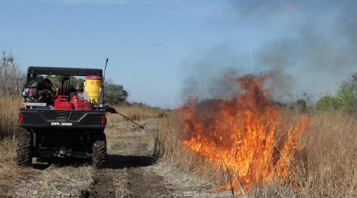 A group of prescribed burn members using a specialized hose to begin the burn in a selected area.