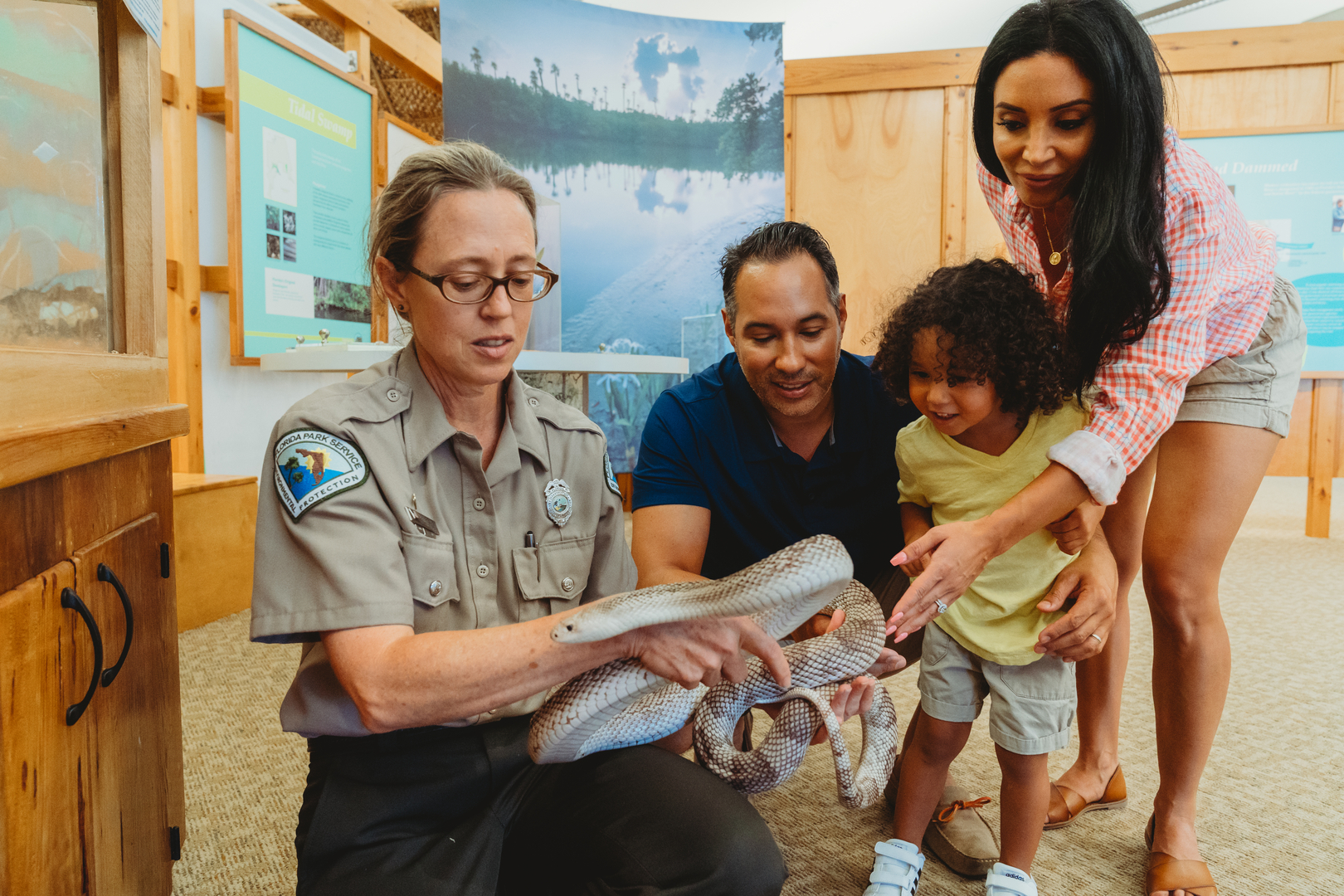Ranger handles a pine snake at visitor center and shows a family. 