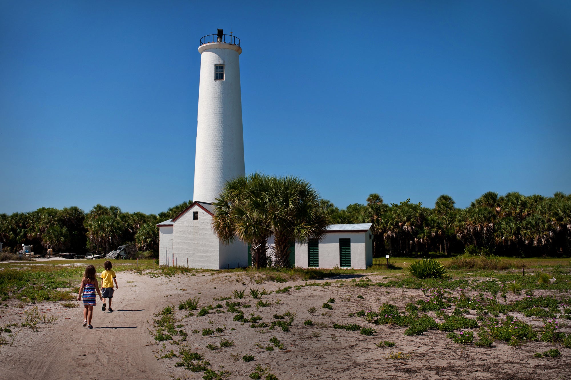 A view of the lighthouse with people walking up to it.