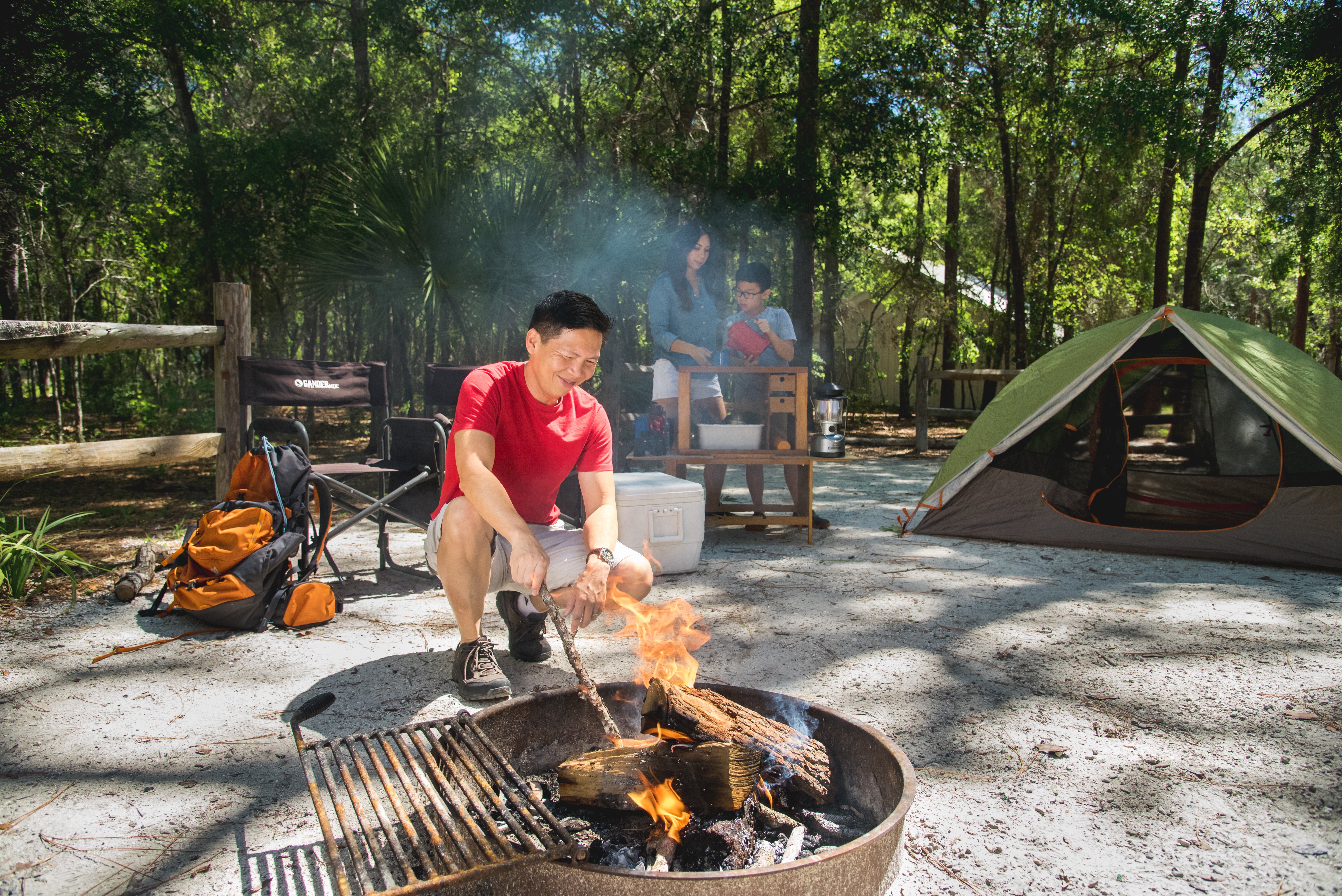 A visitor tends to a campfire at a campsite. 