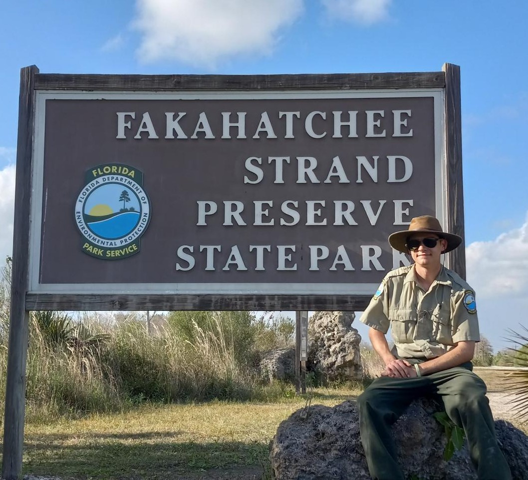 William Greene posing for a photo next to the Fakahatchee Strand Preserve State Park entrance sign.