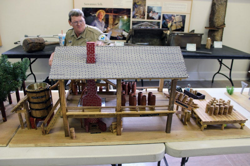 a tiny scale model of a turpentine still, with a ranger in the background