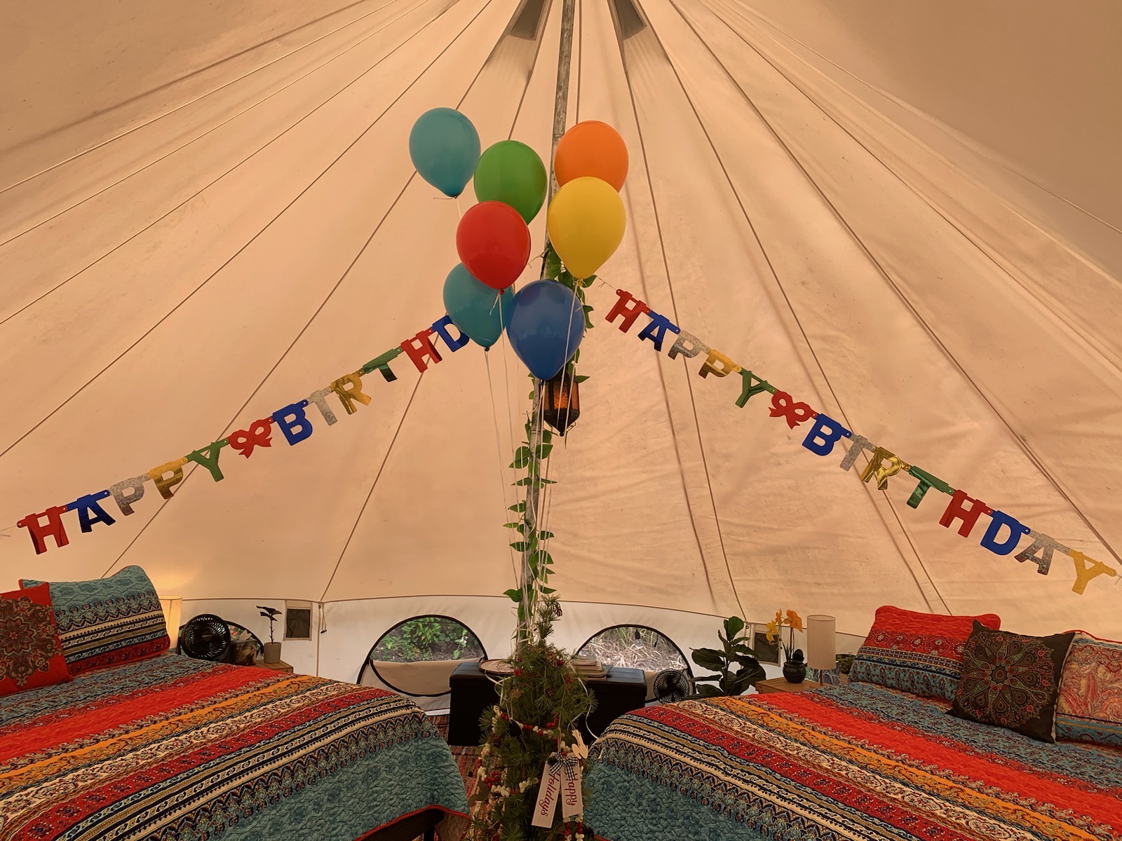 A happy birthday banner and balloons decorate the glamping tent.
