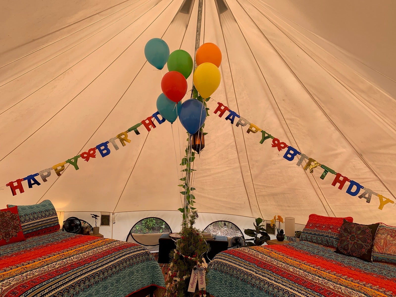 A happy birthday banner and balloons decorate the glamping tent.