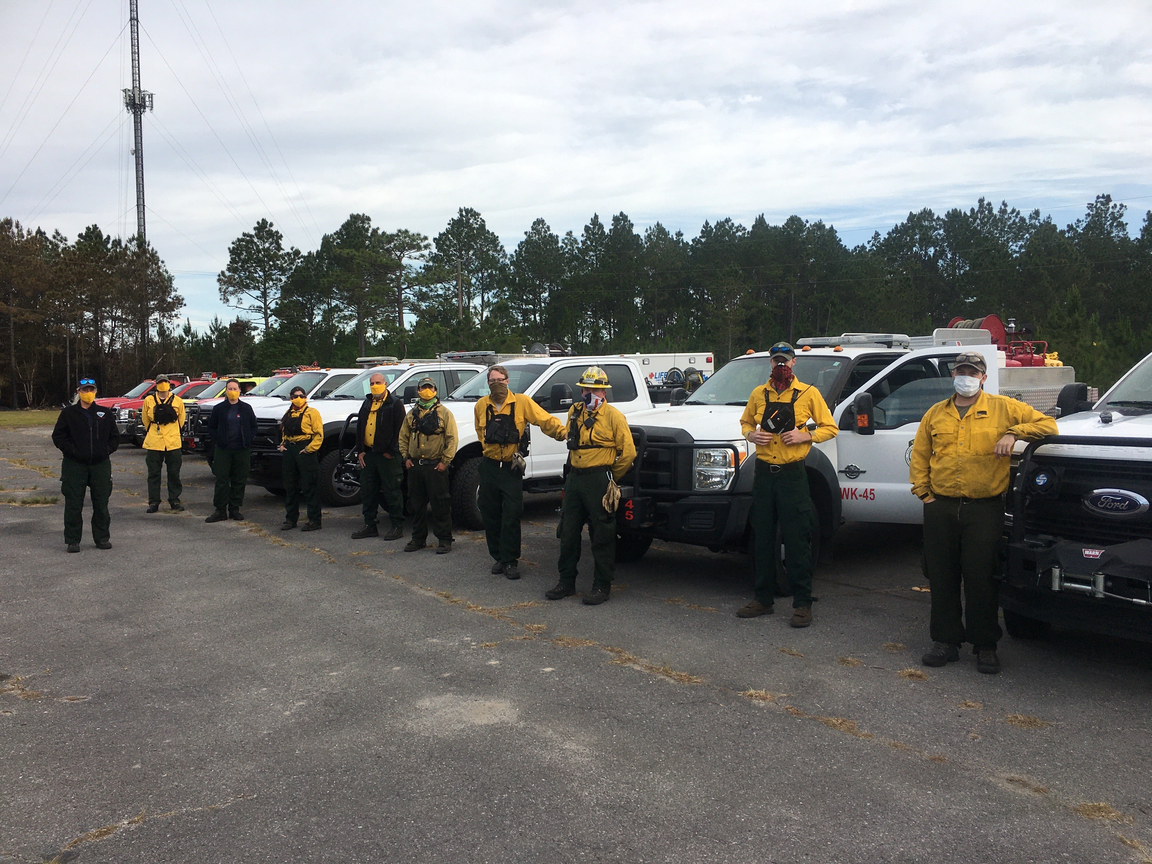 Strike team members stand in front of their fire engines. 