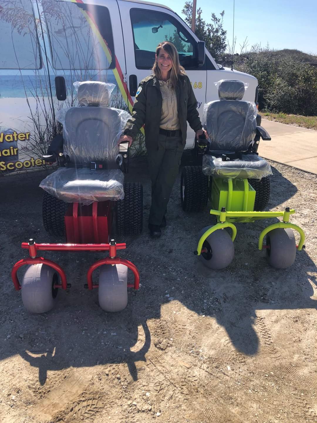 Manager Stephanie McDonald stands with two motorized beach wheelchairs.