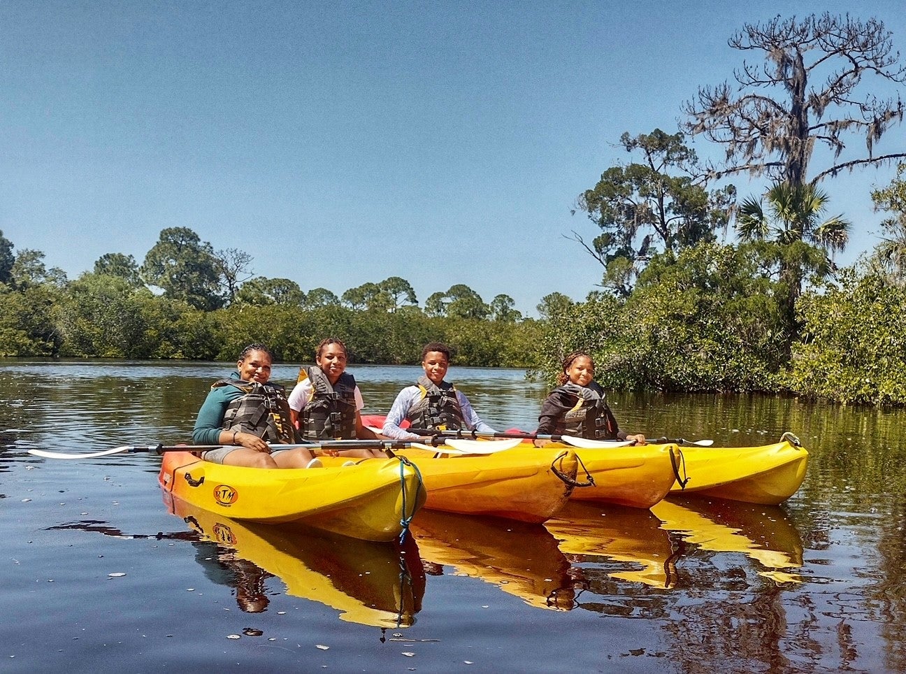 People paddle kayaks.