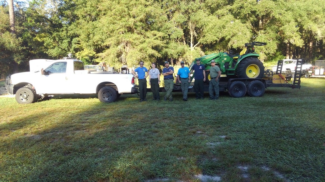 A team of staff in front of a truck and tractor.