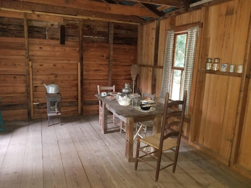 the interior of a small wooden cabin with a tiny kitchen table and stove