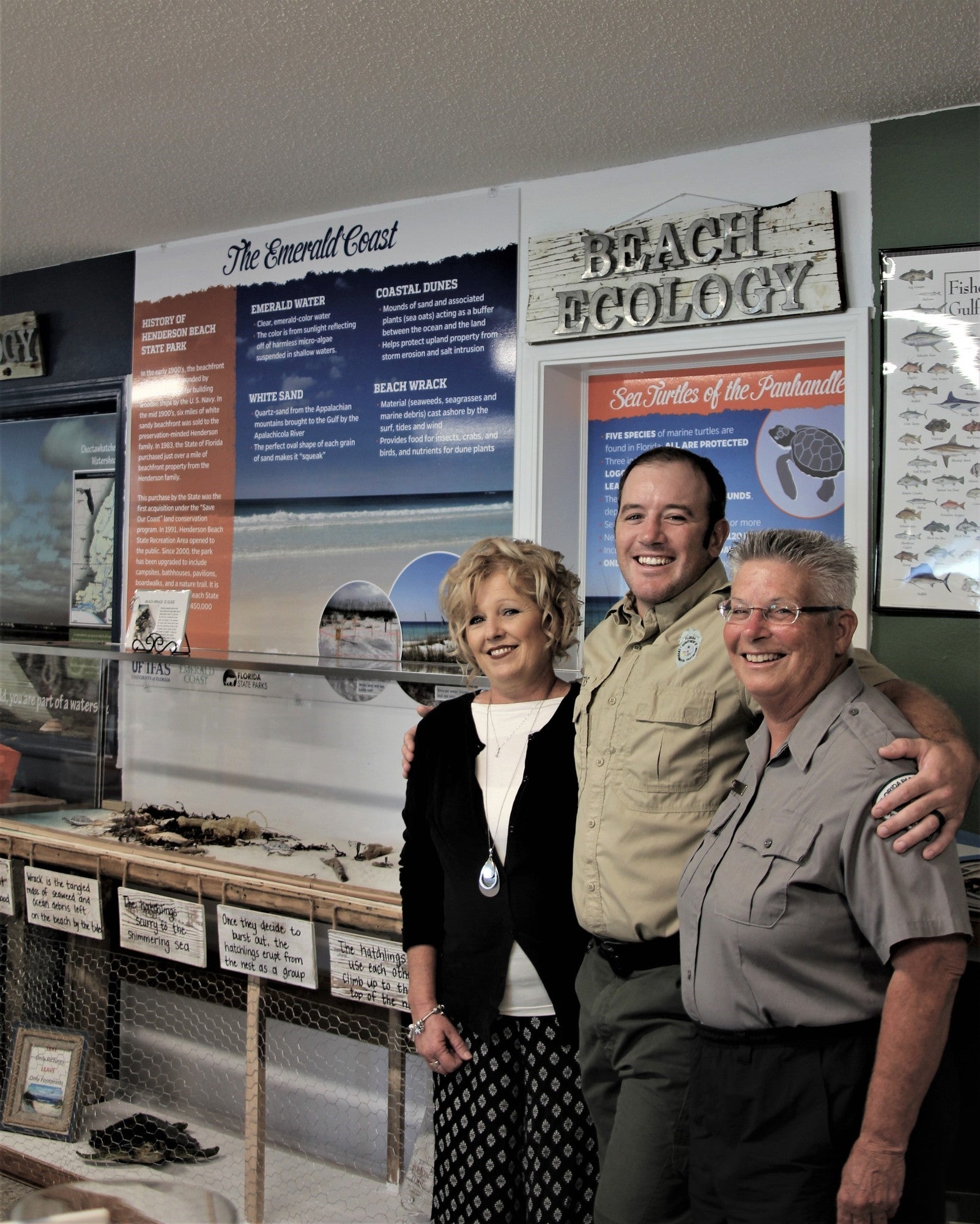 Volunteer Doe Schuster with park staff infront of sea turtle interpretive exhibit.