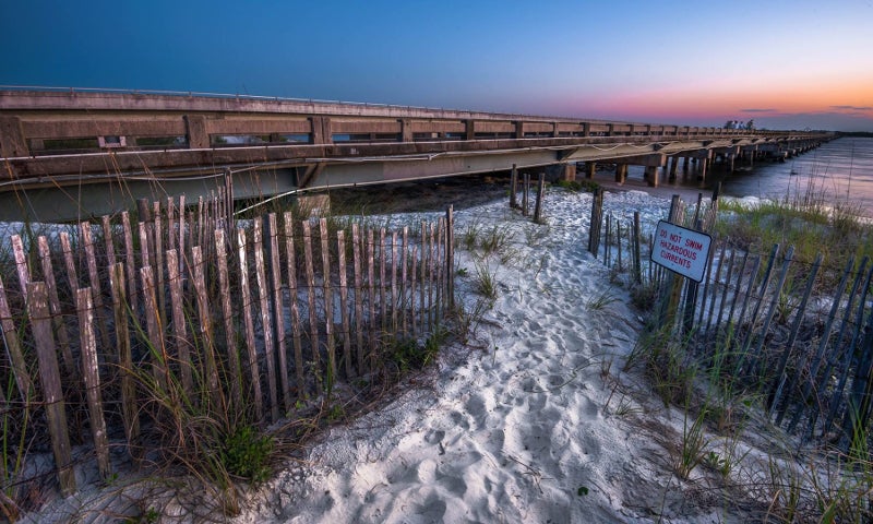 a sandy dune area next to a concrete bridge