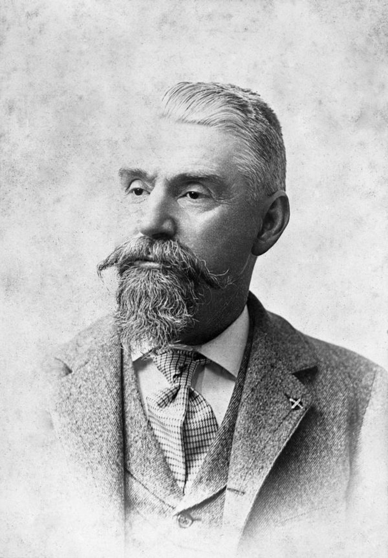 an antique photo of a man in a suit with a large mustache and beard