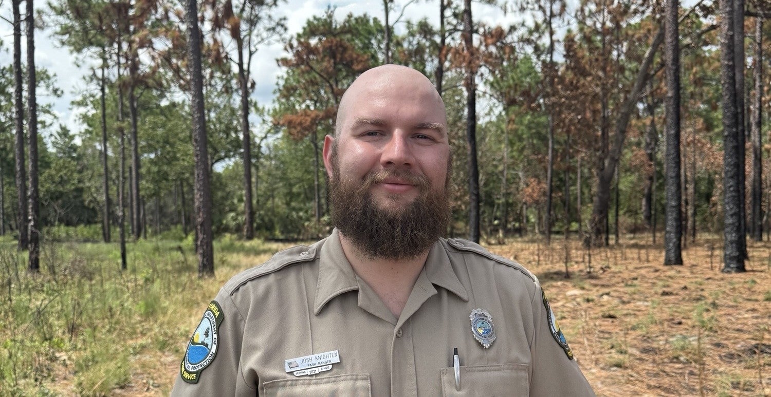Josh Knighten standing in front of a forest.