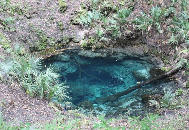 a hole in the ground filled with blue, clear, deep water.