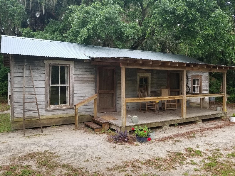 a small wooden cabin type building with a front porch and red flowers