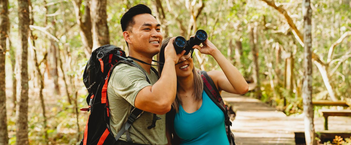 A man and woman look through binoculars to see a bird at Lake Louisa State Park.