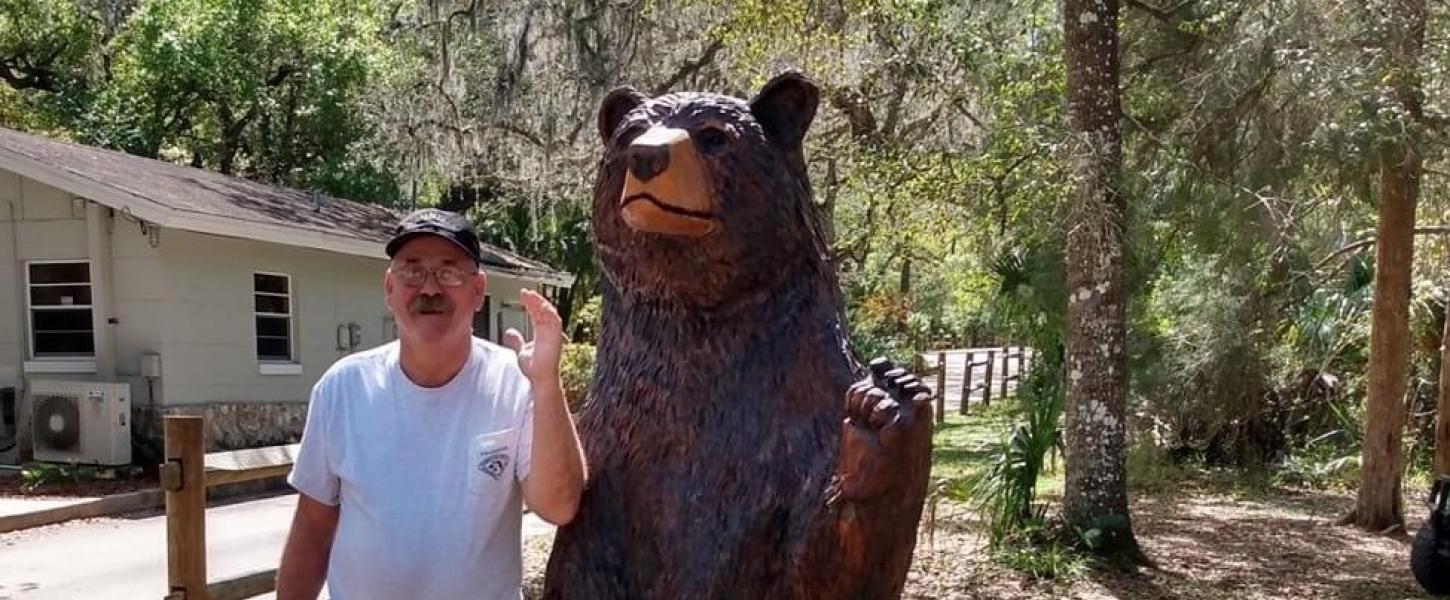Dennis Bryant poses with a bear statue at the park.