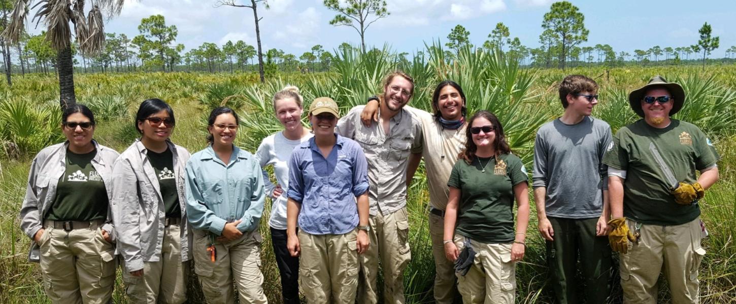 A group of ten FLCC members pose in front of scrub habitat at Savannas Preserve State Park. 