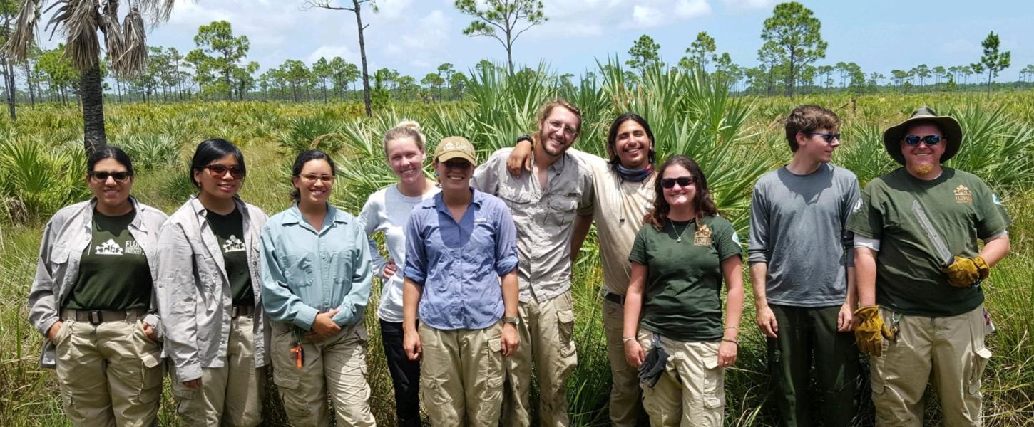 A group of ten FLCC members pose in front of scrub habitat at Savannas Preserve State Park.