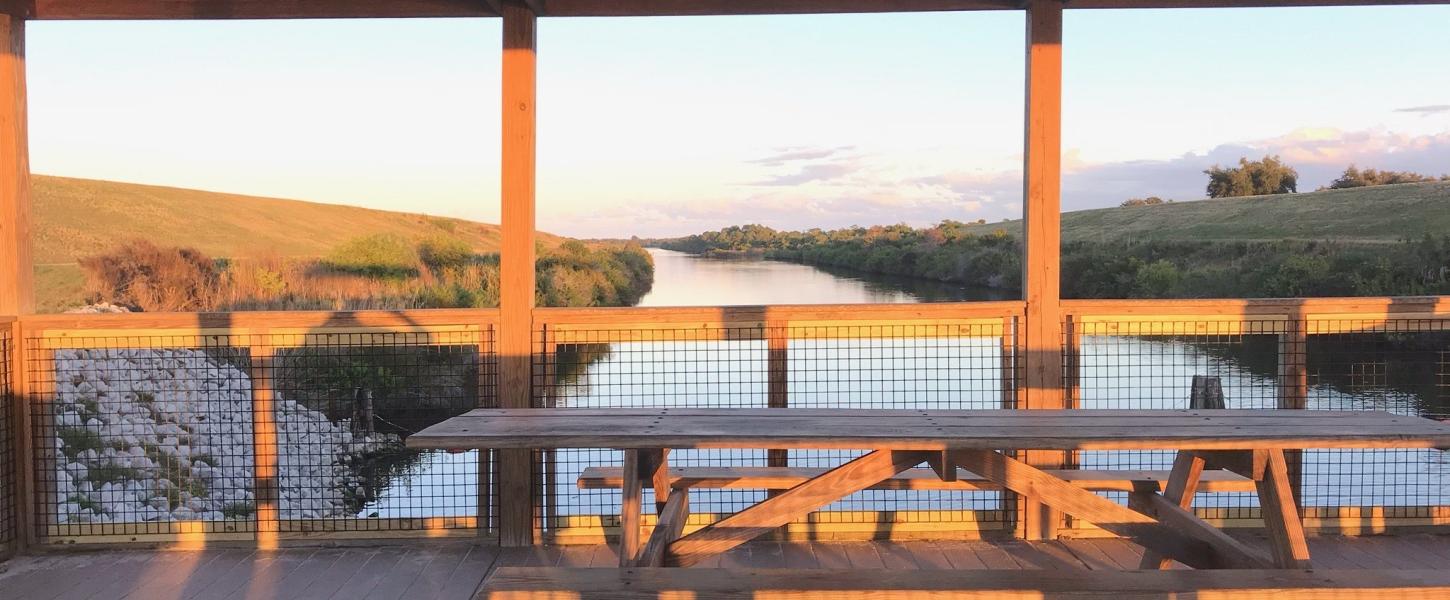 Wooden outlook that has wooden picnic tables during sunset