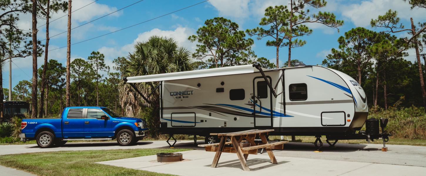 A camper and truck are set up on a concrete pad.