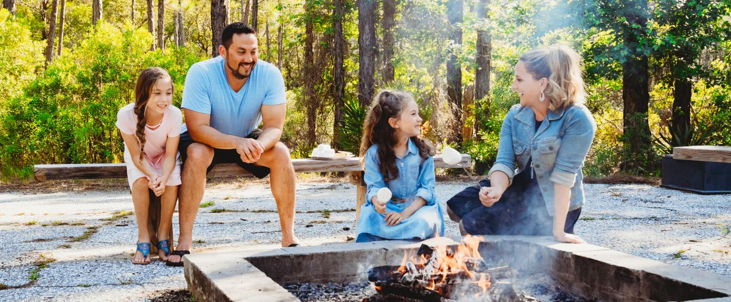 A family of four roasts marshmallows over a fire pit.