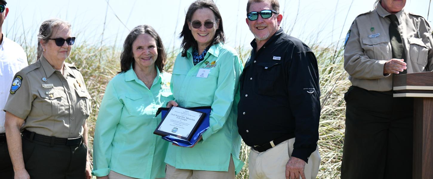 volunteers smile while holding award plaque surrounded by park staff
