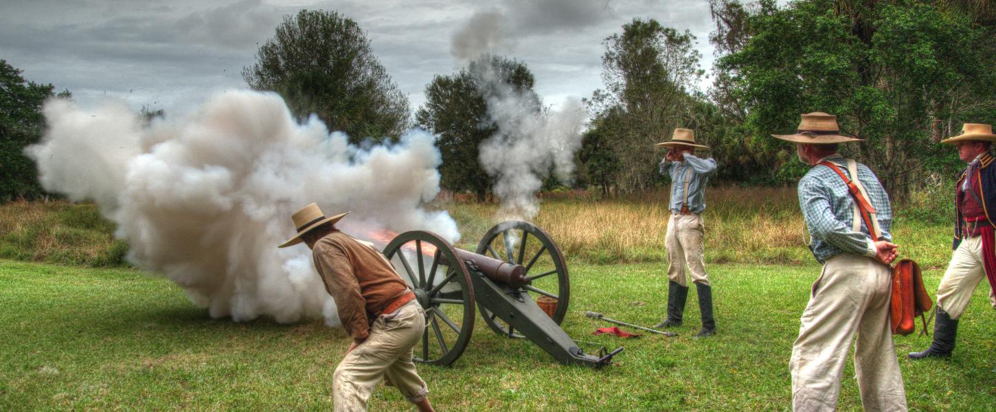 4 Reenactment actors standing around a cannonball firing