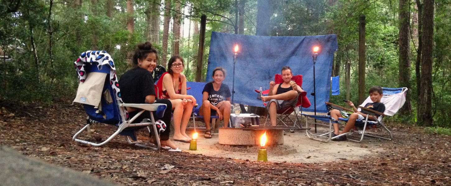 A family sitting around a campfire in a forest. 