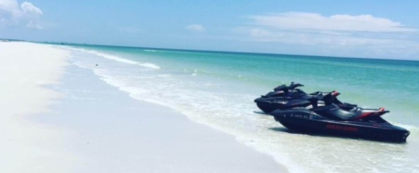 A view of two speedboats on the edge of the water along the beach.