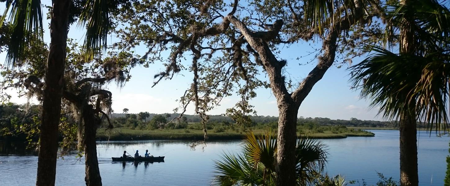 A view of a canoe in the distance floating down the river.