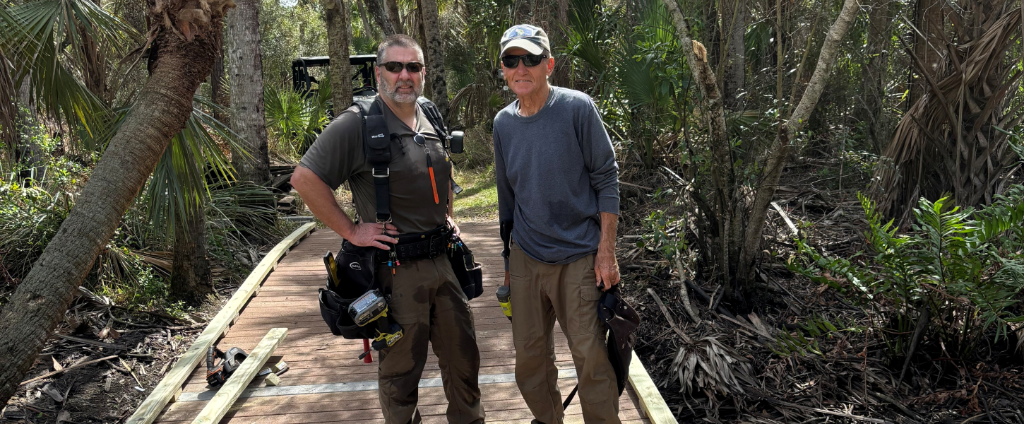 Two men with an assortment of tools standing on a new elevated boardwalk.