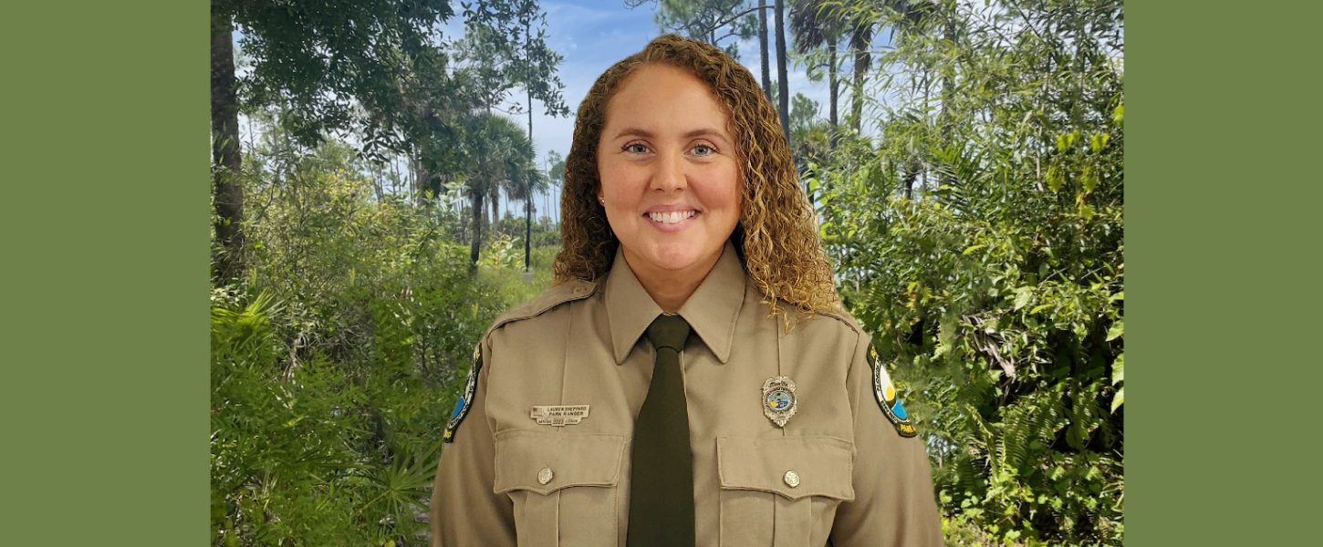 Park Ranger Lauren Sheppard in her uniform standing in the woods.