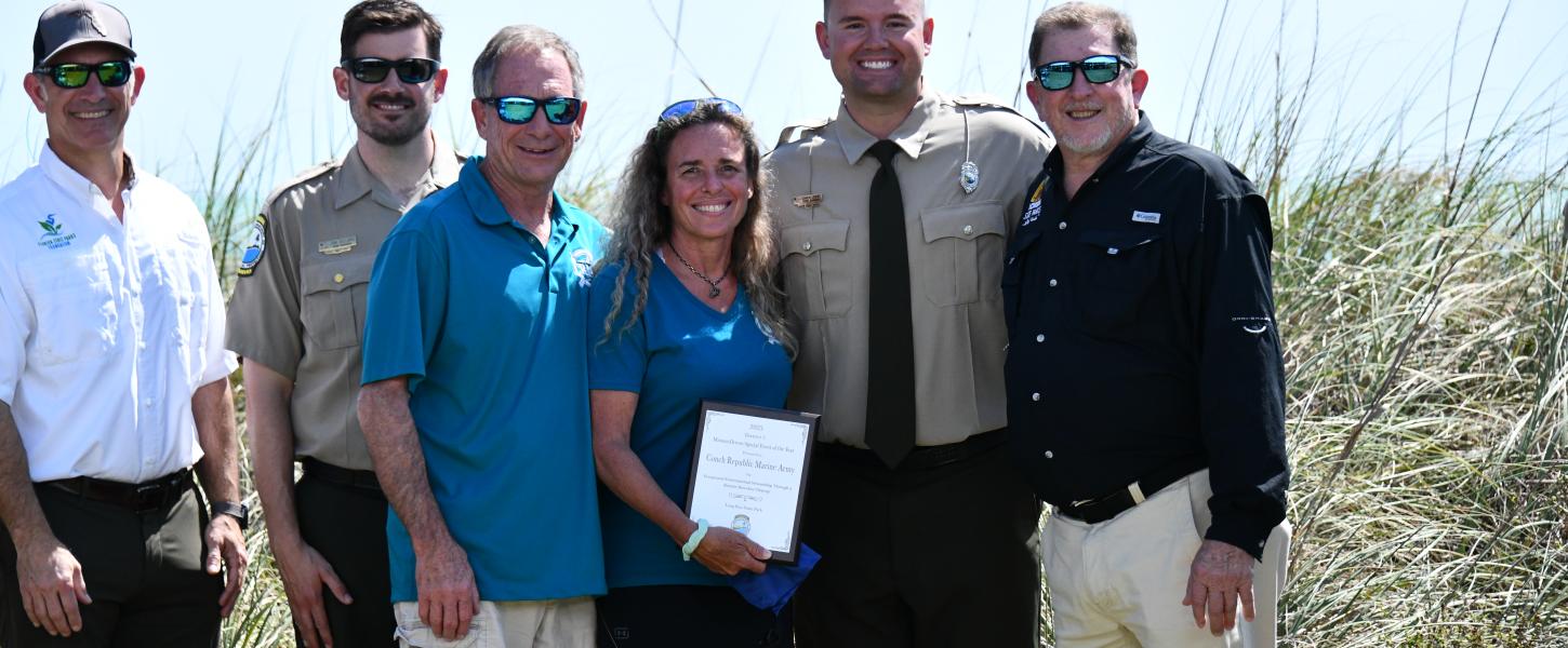 volunteers smile while holding their plaque award surrounded by park staff