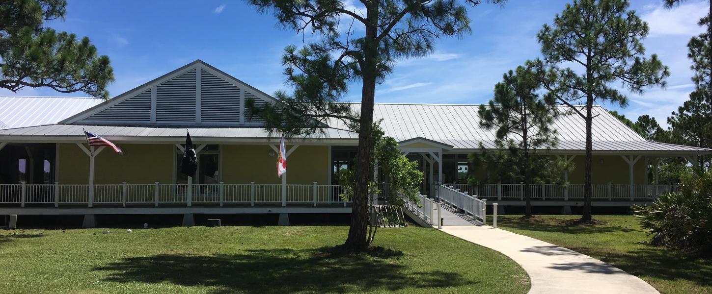 A yellow and white building surrounded by slash pine trees.