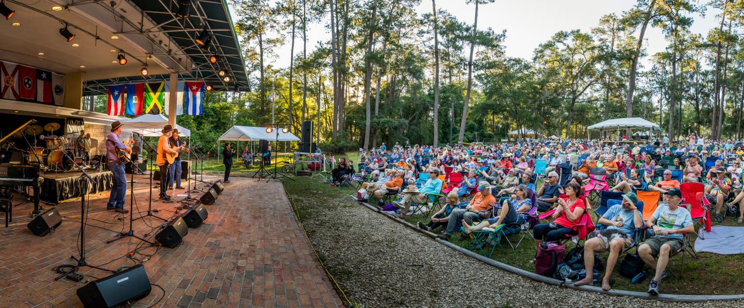 Musicians play on a stage at the festival to a large crowd. 