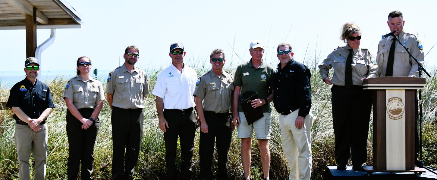 volunteer holds plaque award surrounding by park staff