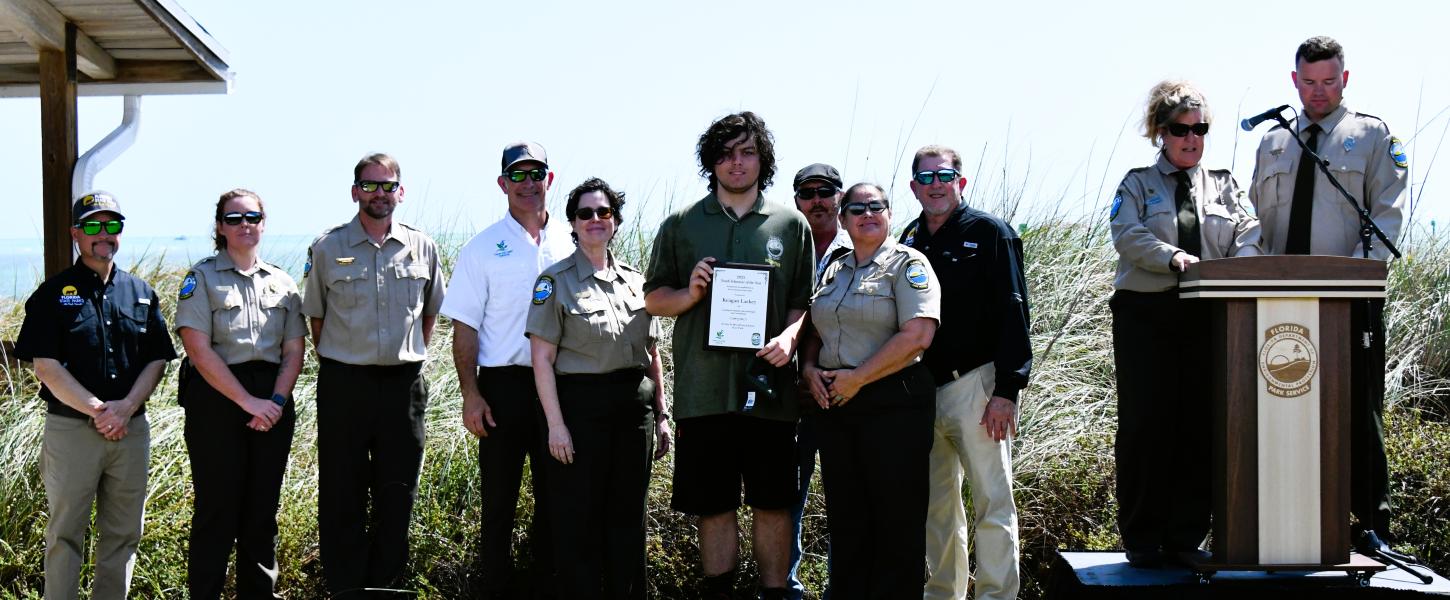 volunteer hold plaque award surrounded by park staff