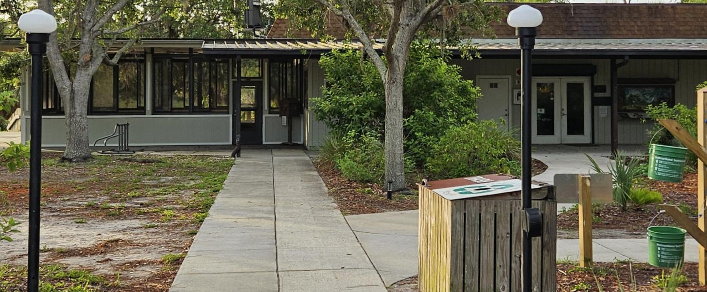 A pathway leading to a low gray and brown building. 